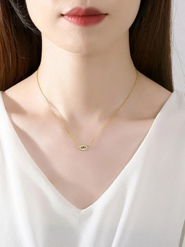 Gold necklace with a small pendant worn by a woman in a white top