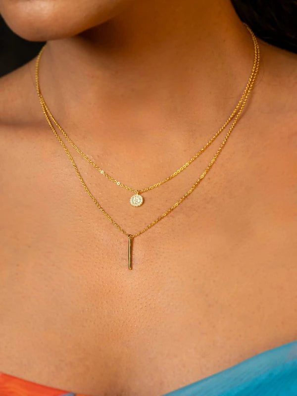 Close-up of a woman wearing two gold necklaces with a blurred background