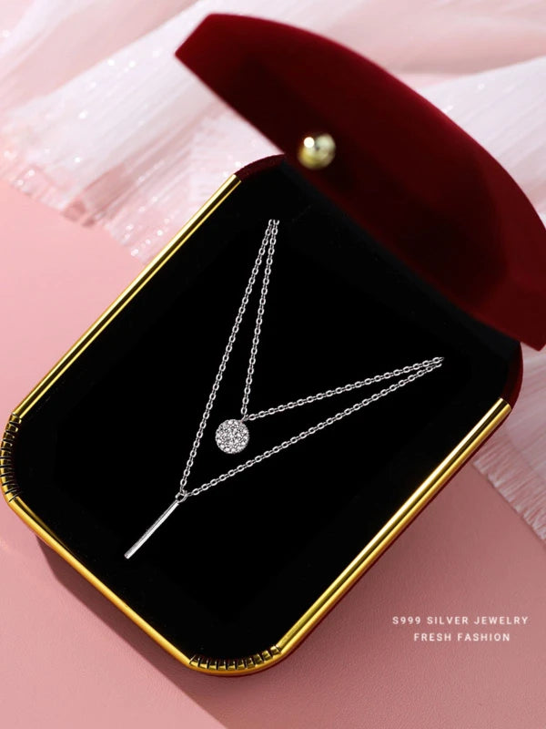 Silver necklace in a black jewelry box on a pink background