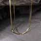 Double layered snake chain necklace on a dark textured surface