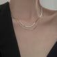 Silver necklace on a mannequin with a plain background