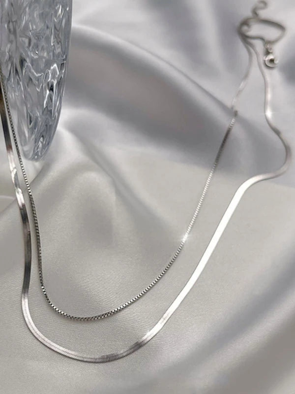 Double layered snake chain necklace on a soft gray fabric background