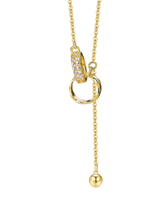 Gold necklace with a heart-shaped clasp and ball pendant on a white background