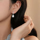Close-up of a person wearing a diamond earring with a neutral background