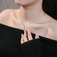 Close-up of a person wearing a necklace with a heart pendant, against a neutral background.