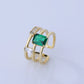 Gold ring with a green gemstone on a light gray background