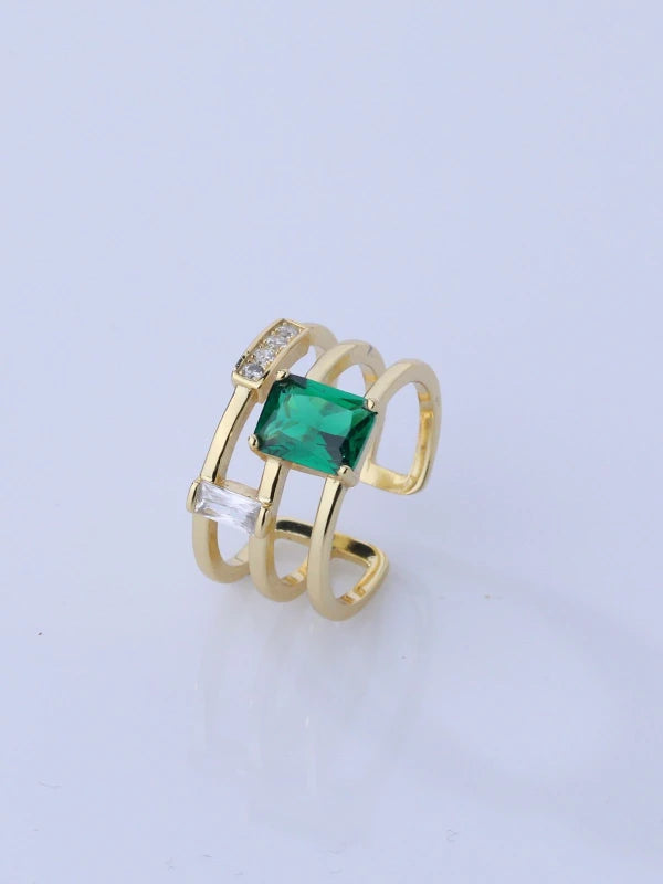 Gold ring with a green gemstone on a light gray background