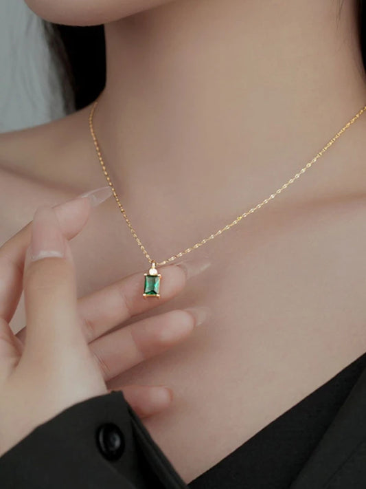 Gold necklace with a green gemstone pendant worn by a woman