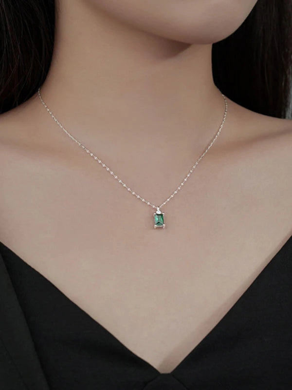 Necklace with a green gemstone pendant on a model wearing a black top.