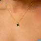 Gold necklace with a green gemstone pendant on a person wearing a blue garment.