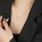 Gold necklace with a heart-shaped pendant worn by a woman in a black outfit.