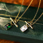 Two gold necklaces with gemstone pendants on a green textured surface.
