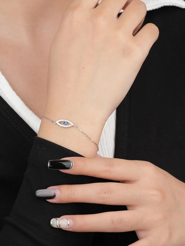 Close-up of a hand wearing a silver bracelet with an eye design 