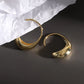 Gold hoop earrings on a dark surface with white paper