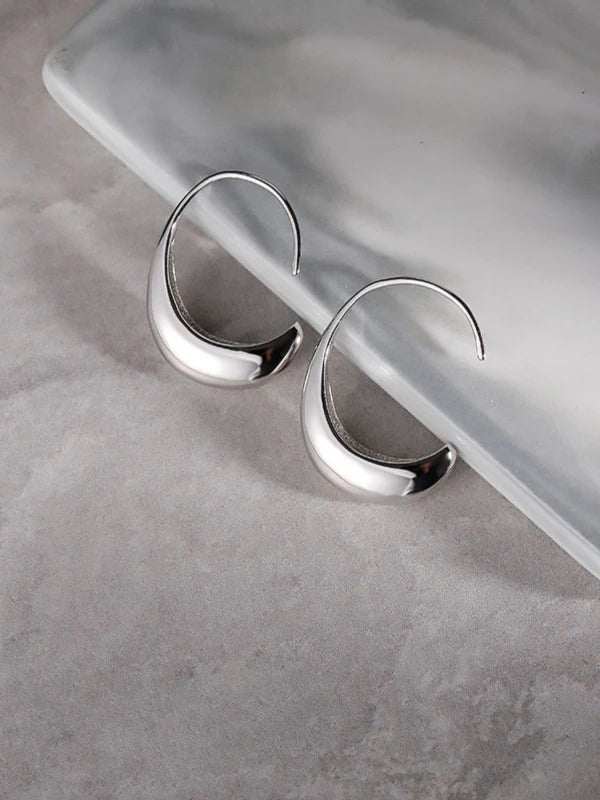 Silver hoop earrings on a gray surface