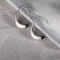 Silver hoop earrings on a gray surface