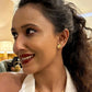 Woman with a ponytail wearing a gold earring and necklace, indoors.