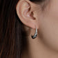 Close-up of an ear wearing a silver hoop earring with a blurred background
