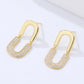 Gold earrings with diamond-like stones on a white background