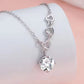 Silver necklace with heart-shaped links and a clear crystal pendant on a soft pink background