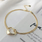 Gold heart-shaped bracelet on a white surface with text