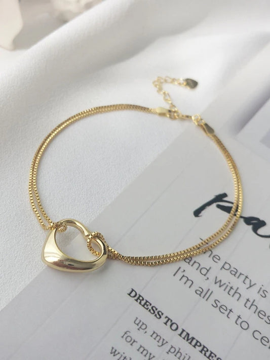 Gold heart-shaped bracelet on a white surface with text