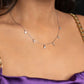 Necklace with small pendants on a woman wearing a purple top.