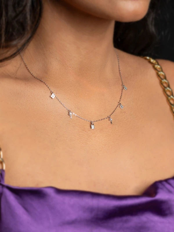 Necklace with small pendants on a woman wearing a purple top.