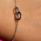 Silver bracelet with interlocking rings on a wrist against a pink background