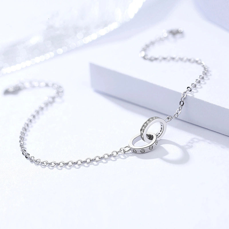 Silver bracelet with a circular clasp on a white background