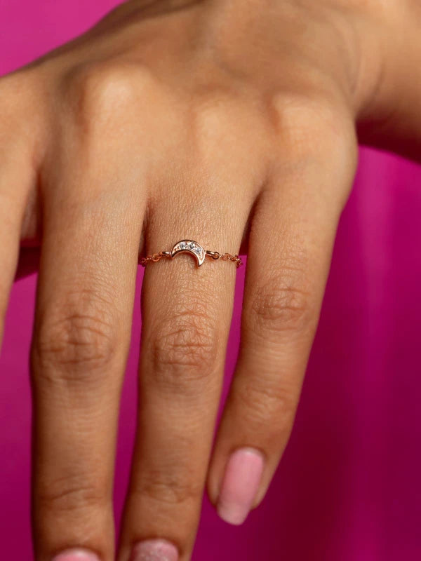 Hand wearing a rose gold ring with a pink background
