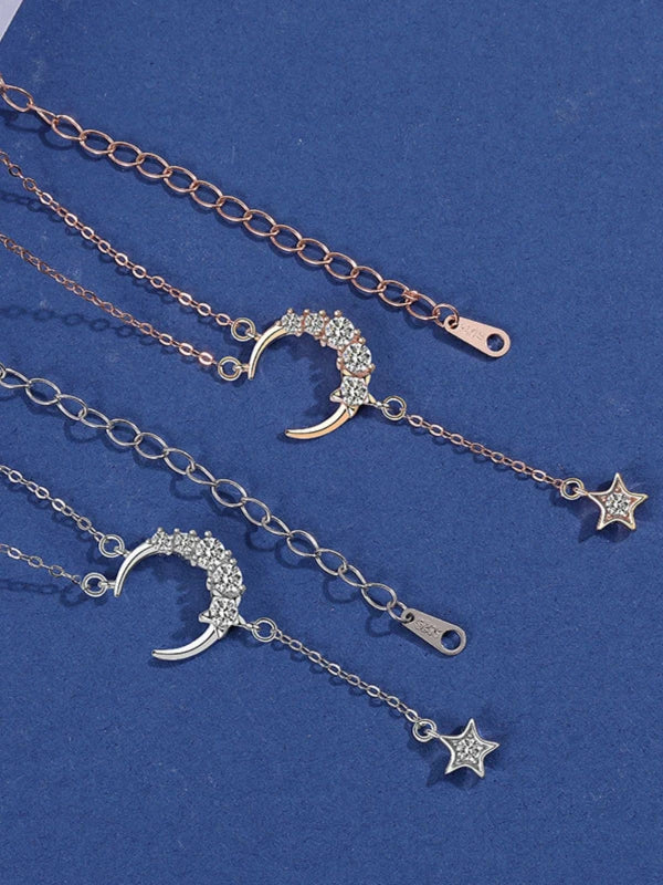 Two silver necklaces with moon and star pendants on a blue background