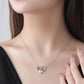 Woman wearing a silver heart-shaped necklace with a clear gemstone.