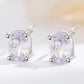 Pair of silver earrings with purple gemstones on a light background