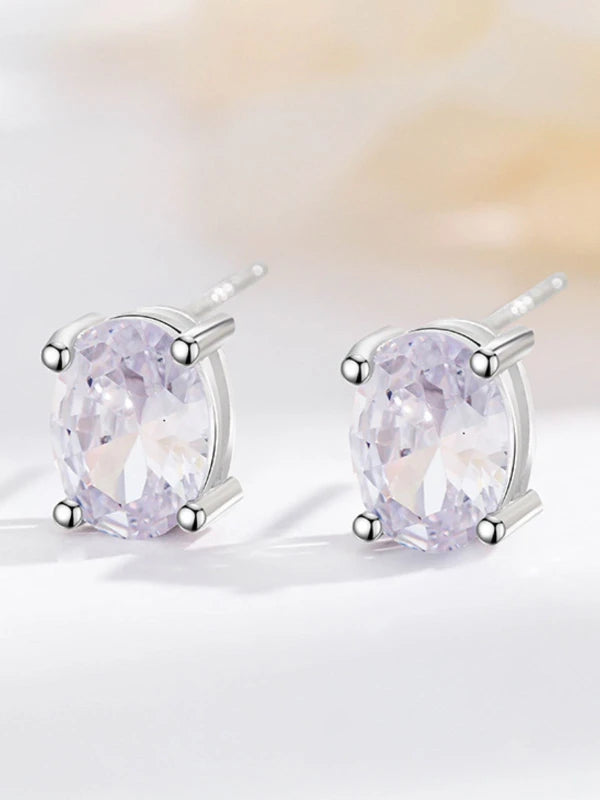 Pair of silver earrings with purple gemstones on a light background