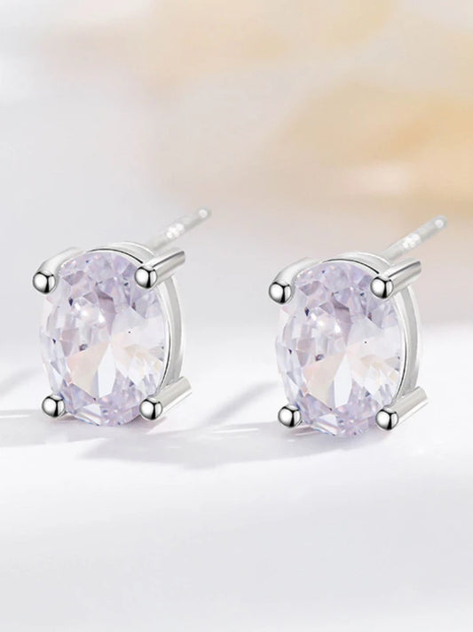 Pair of silver earrings with purple gemstones on a light background