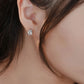 Close-up of an ear wearing a diamond earring with a blurred background