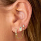 Close-up of an ear wearing gold hoop earrings with a small blue gemstone.