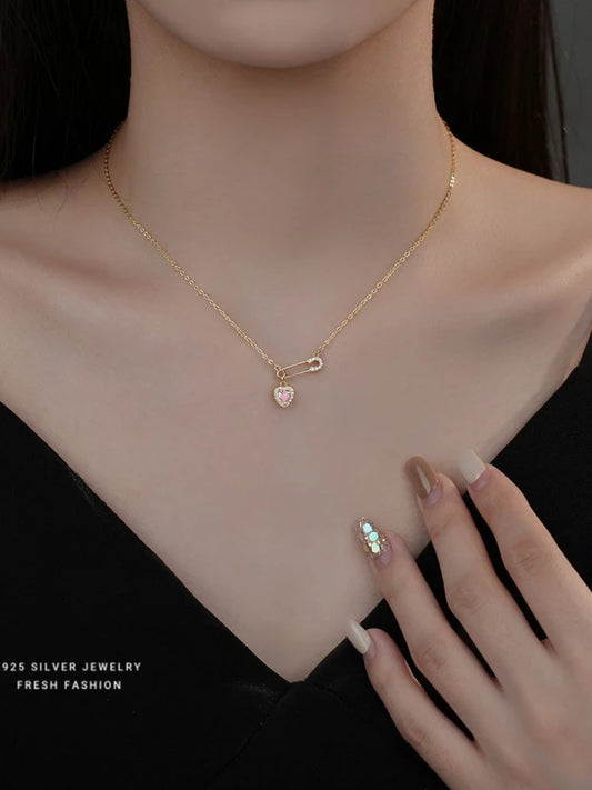 Gold necklace with a heart-shaped pendant on a woman's neck.
