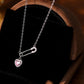 Silver necklace with a pink heart pendant on a dark surface