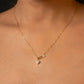 Gold necklace with a heart-shaped pendant on a person's neck