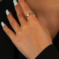 Hand with light green nail polish wearing a gold ring on a black background