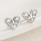 Heart-shaped silver earrings with clear gemstones on a light background