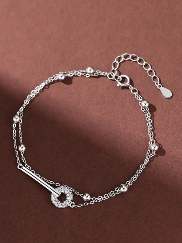 Silver bracelet with a key charm on a brown background