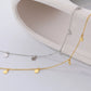 Two gold necklaces with small round pendants on a white surface.