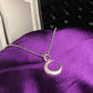 Silver crescent moon necklace on a purple fabric background