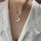 Silver necklace with a crescent moon pendant on a white blouse