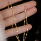 Gold chain necklace on a hand against a dark background