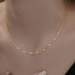 Gold necklace being worn on a woman's neck with a neutral background