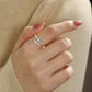 Close-up of a hand wearing a diamond ring with a blurred background